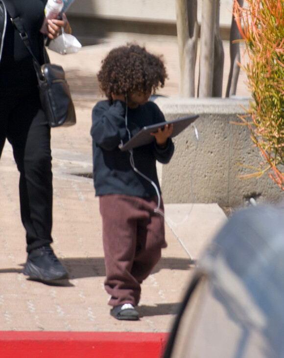 Exclusif - Saint West - North West, 6 ans, et son frère Saint West, 4 ans, sont de retour à la maison, les yeux rivés sur leurs tablettes, avec la nourrice à leurs côtés à Calabasas, le 23 mars 2020.