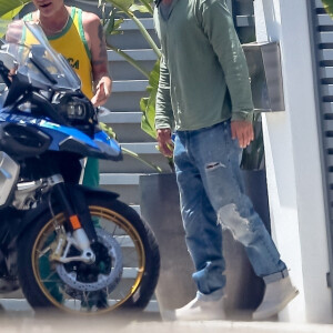 Exclusif - Brad Pitt sort devant son domicile pour voir la nouvelle moto du musicien Flea à Malibu le 24 mai 2020. Brad, cheveux long, examine la nouvelle BMW R1250 de son ami tandis que Flea lui fait une présentation digne d'un vendeur.