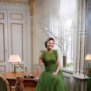 Au palais Haga, la princesse Victoria (en robe H&M Conscious) pose avec son prix de la personnalité hétéro de l'année 2021, remis par le magazine scandinave QX.