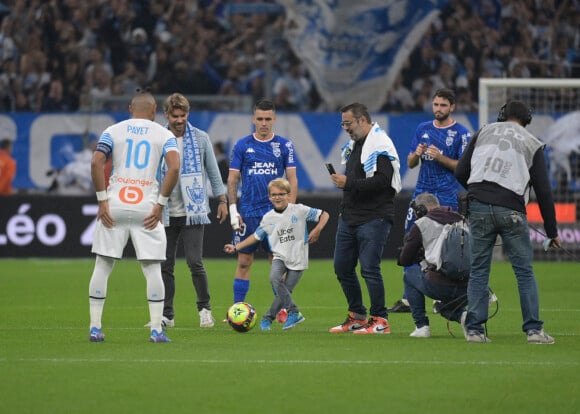 En hommage à Bernard Tapie, son petit-fils Rodolphe, accompagné de son oncle Stéphane Tapie, et son fils Hugo a donné le coup d'envoi du match de Ligue 1 Uber Eats "Marseille - Lorient (4-1)" au stade Vélodrome à Marseille, le 17 octobre 2021.