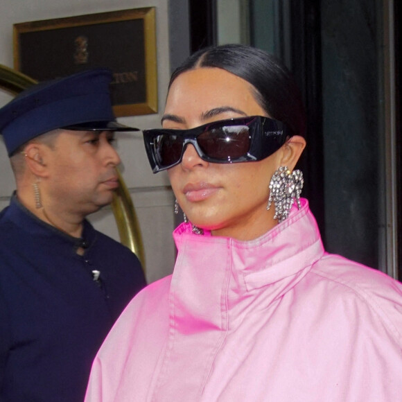 Kim Kardashian (emmitouflée dans un long manteau rose) et Kanye West sortent ensemble de l'hôtel Ritz Carlton pour se rendre dans les studios de l'émission "Saturday Night Live" (SNL) à New York, le 9 octobre 2021. 