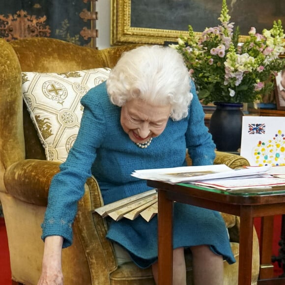 La reine Elisabeth II est rejointe par l'un de ses chiens, un Dorgi appelé Candy, alors qu'elle regarde une exposition de souvenirs de ses jubilés d'or et de platine dans la salle Oak du château de Windsor2022.