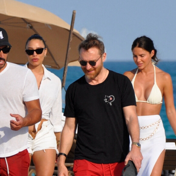 David Guetta et sa compagne Jessica Ledon, avec son ami le DJ Cédric Gervais et sa fiancée Adriana Gutierrez, sur la plage du palace Setai à Miami, le 20 mars 2022.
