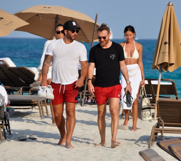 David Guetta et sa compagne Jessica Ledon, avec son ami le DJ Cédric Gervais et sa fiancée Adriana Gutierrez, sur la plage du palace Setai à Miami, le 20 mars 2022.