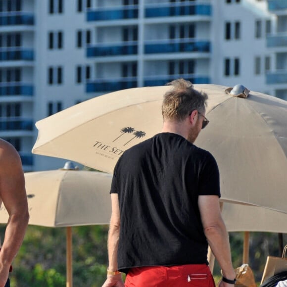David Guetta et sa compagne Jessica Ledon, avec son ami le DJ Cédric Gervais et sa fiancée Adriana Gutierrez, sur la plage du palace Setai à Miami, le 20 mars 2022.