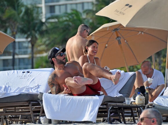 David Guetta et sa compagne Jessica Ledon, avec son ami le DJ Cédric Gervais et sa fiancée Adriana Gutierrez, sur la plage du palace Setai à Miami, le 20 mars 2022.