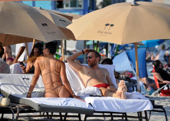 David Guetta et sa compagne Jessica Ledon, avec son ami le DJ Cédric Gervais et sa fiancée Adriana Gutierrez, sur la plage du palace Setai à Miami, le 20 mars 2022.