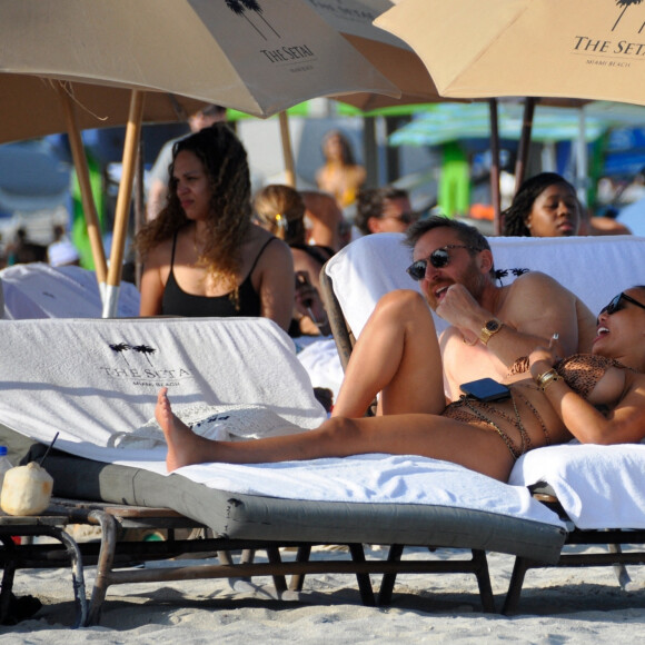 David Guetta et sa compagne Jessica Ledon, avec son ami le DJ Cédric Gervais et sa fiancée Adriana Gutierrez, sur la plage du palace Setai à Miami, le 20 mars 2022.