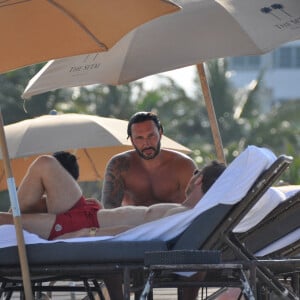 David Guetta et sa compagne Jessica Ledon, avec son ami le DJ Cédric Gervais et sa fiancée Adriana Gutierrez, sur la plage du palace Setai à Miami, le 20 mars 2022.