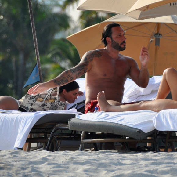David Guetta et sa compagne Jessica Ledon, avec son ami le DJ Cédric Gervais et sa fiancée Adriana Gutierrez, sur la plage du palace Setai à Miami, le 20 mars 2022.