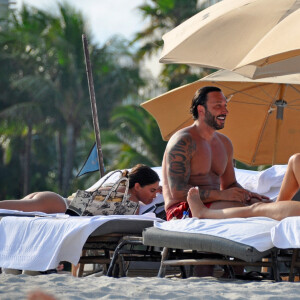 David Guetta et sa compagne Jessica Ledon, avec son ami le DJ Cédric Gervais et sa fiancée Adriana Gutierrez, sur la plage du palace Setai à Miami, le 20 mars 2022.