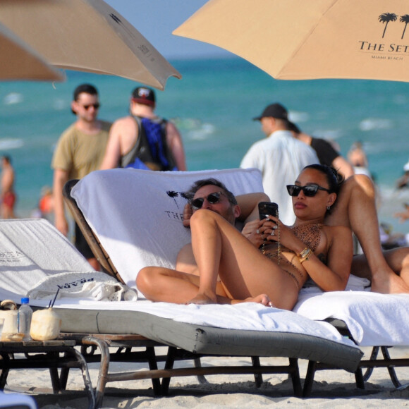 David Guetta et sa compagne Jessica Ledon, avec son ami le DJ Cédric Gervais et sa fiancée Adriana Gutierrez, sur la plage du palace Setai à Miami, le 20 mars 2022.