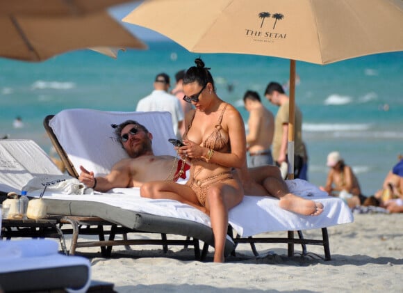 David Guetta et sa compagne Jessica Ledon, avec son ami le DJ Cédric Gervais et sa fiancée Adriana Gutierrez, sur la plage du palace Setai à Miami, le 20 mars 2022.