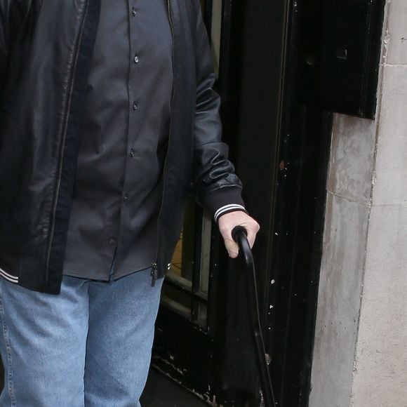 Phil Collins marche avec une canne en se rendant aux studios de la BBC Radio Two à Londres, le 26 janvier 2016, pour faire la promotion de son nouvel album. 