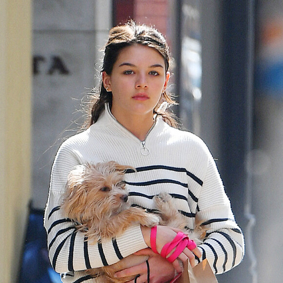 Suri Cruise, la fille de T.Cruise et K.Holmes, porte son chien dans ses bras dans les rues de New York, le 16 mars 2022. 
