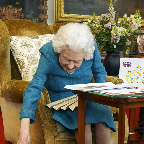 La reine Elisabeth II est rejointe par l'un de ses chiens, un Dorgi appelé Candy, alors qu'elle regarde une exposition de souvenirs de ses jubilés d'or et de platine dans la salle Oak du château de Windsor2022. 