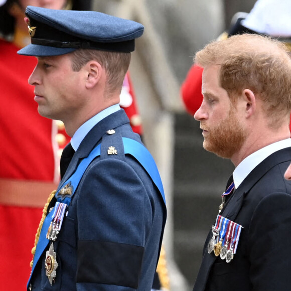 Le prince William, prince de Galles et son frère le prince Harry lors de la procession vers l'abbaye de Westminster où se tiennent les funérailles d'Elizabeth II. Les deux hommes se distinguent par leur tenue - Harry ne peut porter d'uniforme militaire car il a renoncé à ses fonctions royales - mais se retrouvent dans leur émotion.