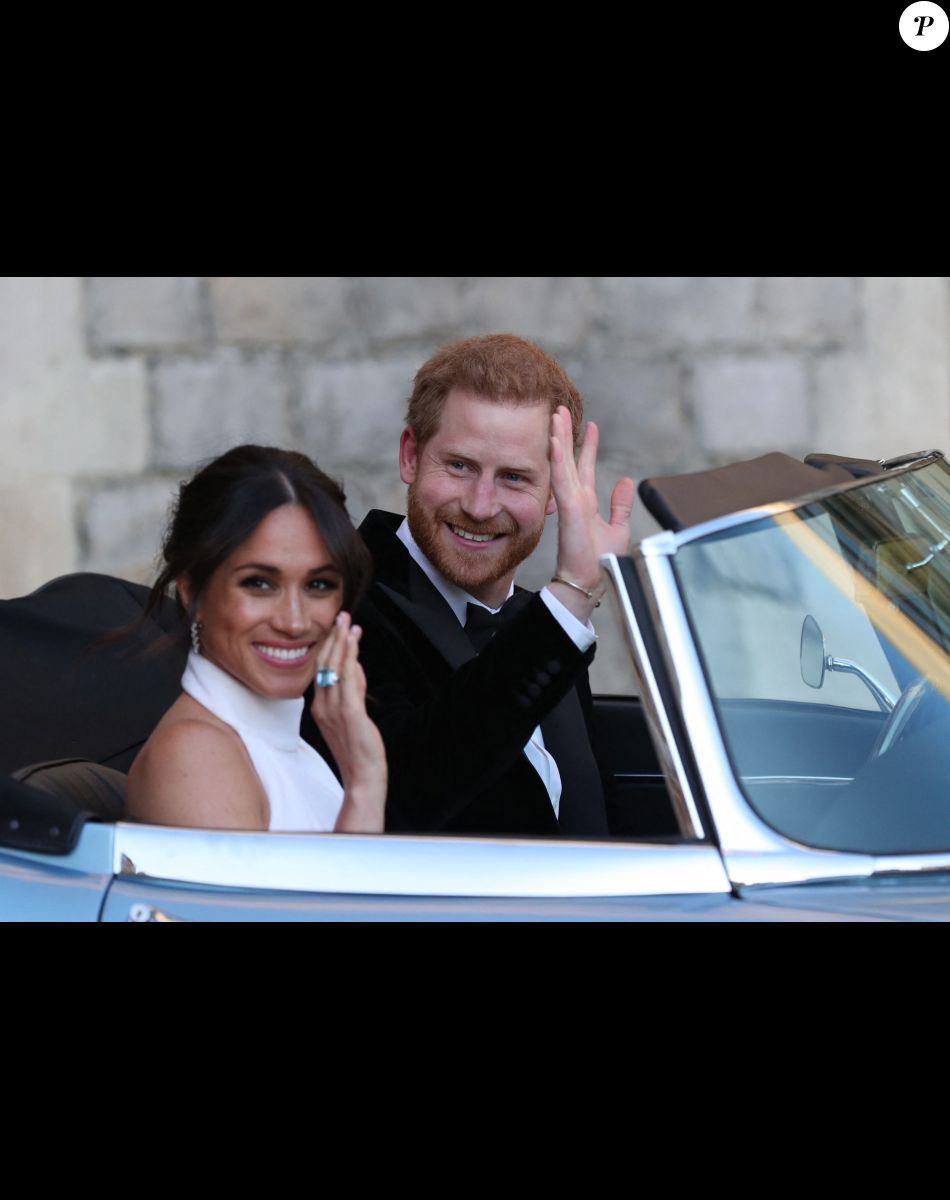 Le prince Harry, duc de Sussex, et Meghan Markle, duchesse de Sussex quittent le château de Windsor à bord d'une Jaguar Type E cabriolet en tenue de soirée après leur cérémonie de mariage, pour se rendre à la réception à "Frogmore House" à Windsor le 19 mai 2018.