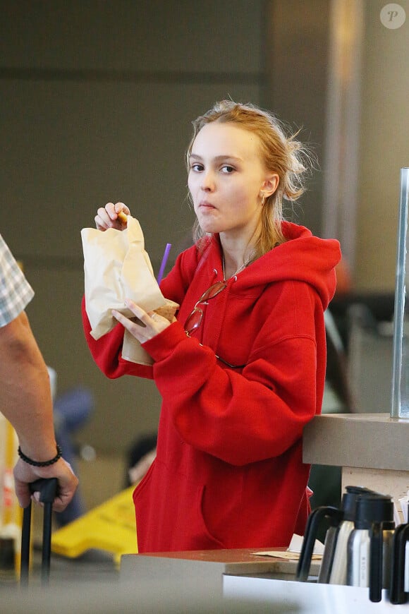 Lily-Rose Depp fait la queue au comptoir "The Coffee Bean" à l'aéroport de Los Angeles, commande puis mange un snack avec une boisson rapidement avant d'aller prendre un avion accompagnée de son garde du corps le 22 mai 2016.