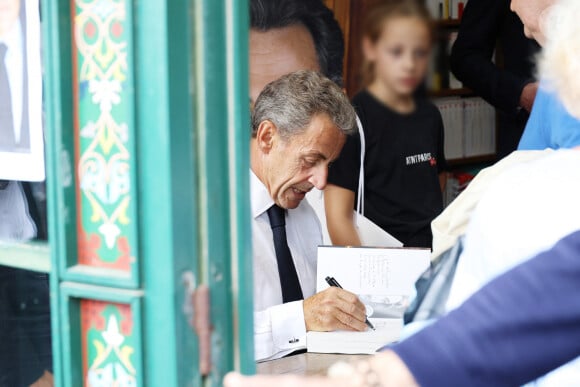 L'ancien président de la République française Nicolas Sarkozy dédicace son livre "Le temps des Combats" sous l'oeil attentif de sa fille Giulia à la Librairie du Marché à Deauville, France, le 1er septembre 2023. © Denis Guignebourg/Bestimage 