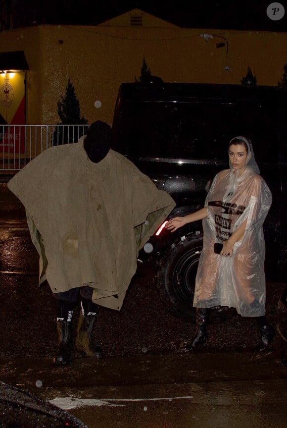 Exclusif - Kanye West, portant un masque intégral et un poncho, avec sa femme Bianca Censori, nue en imperméable transparent, arrivent à un studio à Los Angeles, le 5 février 2024. 