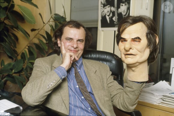 En France, à Paris, le directeur des programmes de Canal+, Alain De Greef assis à son bureau, tenant une tete de marionnette du guignol à son effigie en janvier 1991