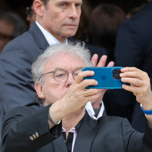 Dominique Besnehard photographie la foule massée devant la salle de la Coupole du crématorium du cimetière du Père-Lachaise - Sortie des obsèques de l'auteure-compositrice-interprète et actrice française Françoise Hardy au crématorium du cimetière du Père-Lachaise à Paris, France, le 20 juin 2024. © Jacovides-Moreau/Bestimage 