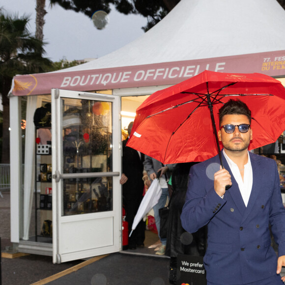 Kev Adams brave la pluie avec un parapluie rouge lors de la première journée du 77ème Festival de Cannes au Palais des Festivals à Cannes, France, le 14 mai 2024, dans le cadre du programme Photo by Cyril CHATEAU/ABACAPRESS.COM