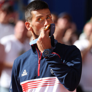 Le Serbe Novak Djokovic brandit sa médaille d'or après sa victoire en finale du simple messieurs contre l'Espagnol Carlos Alcaraz à Roland Garros lors de la neuvième journée des Jeux Olympiques de Paris, le dimanche 04 août 2024.