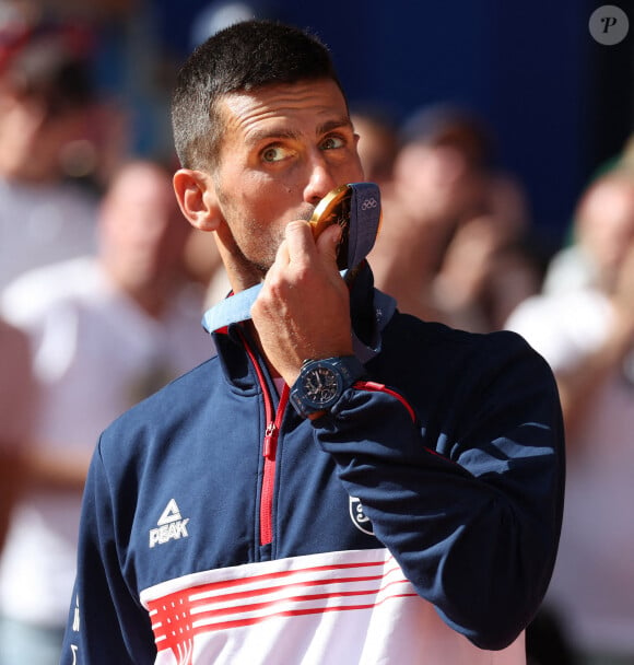 Le Serbe Novak Djokovic brandit sa médaille d'or après sa victoire en finale du simple messieurs contre l'Espagnol Carlos Alcaraz à Roland Garros lors de la neuvième journée des Jeux Olympiques de Paris, le dimanche 04 août 2024.