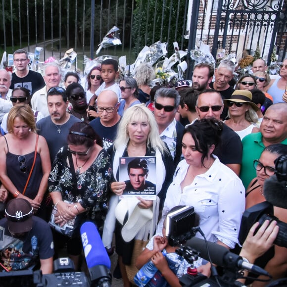 Les fans rendent hommage à Alain Delon à 17 heures en chantant la chanson "Paroles Paroles" avec la pluie qui arrive juste à la fin comme un signe devant la propriété de l'acteur au moment de ses obsèques à Douchy-Montcorbon le 24 août 2024. © Baptiste Autissier / Panoramic / Bestimage