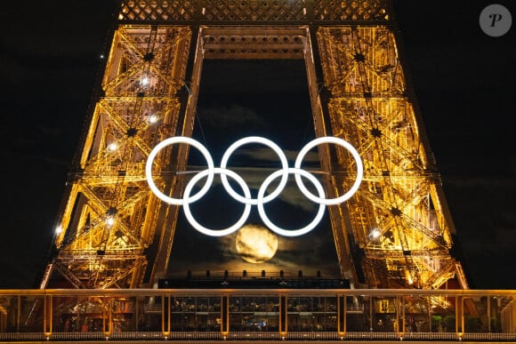 Illustrations de la pleine lune alignée sur les anneaux olympiques de la Tour Eiffel à Paris, le 20 juillet 2024. 