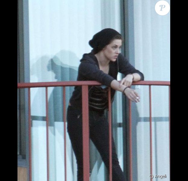 De retour à son hôtel après une balade sur un bateau, Kristen Stewart fume une cigarette sur le balcon de sa chambre... et adresse un petit signe gracieux aux photographes, le dimanche 30 mai à Sydney, en Australie.