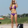 Jessica Hart s'amuse sur la plage. Son bikini violet lui va à ravir.