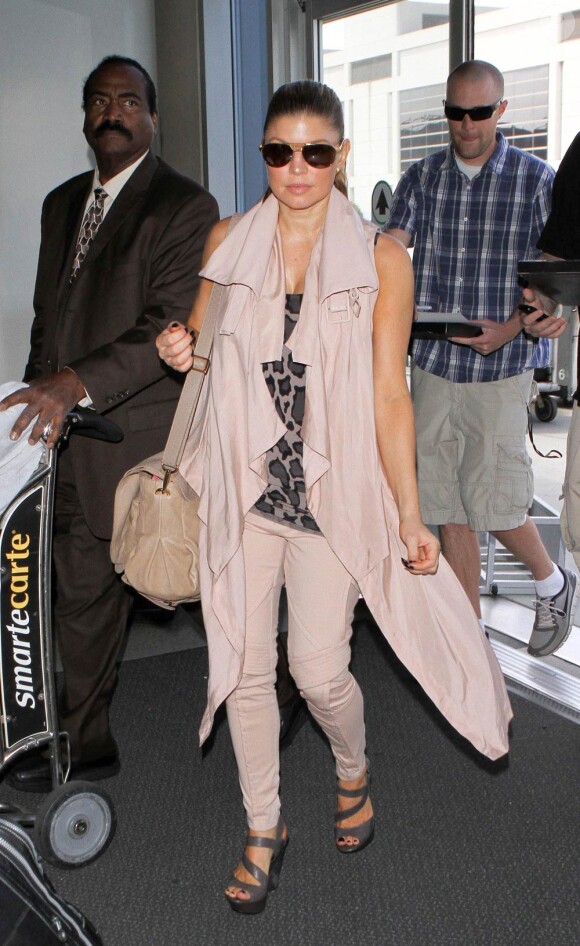 Fergie, à l'aéroport de Los Angeles, se fait fouiller par un agent au sol, lors de son passage au contrôle de sécurité. 17 avril 2011