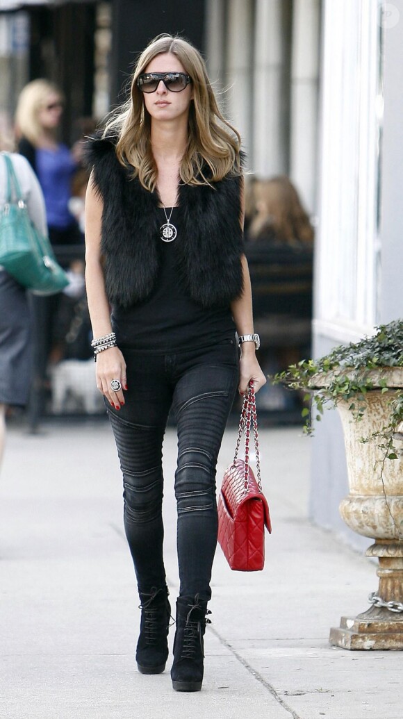 Nicky Hilton porte la fourrure en accessoire avec ce petit gilet, sur un jean Balmain et des mini-bottes noires.