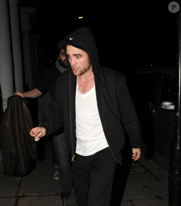Robert Pattinson tente de se cacher et de s'éloigner de Kristen Stewart lorsqu'ils rentrent dans leur appartement de Notting Hill après un concert de leur ami Marcus Foster chez Bar Dingwalls à Londres le 23 novembre 2011