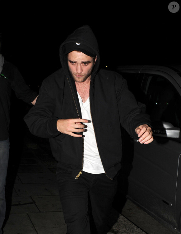 Robert Pattinson tente de se cacher et de s'éloigner de Kristen Stewart lorsqu'ils rentrent dans leur appartement de Notting Hill après un concert de leur ami Marcus Foster chez Bar Dingwalls à Londres le 23 novembre 2011