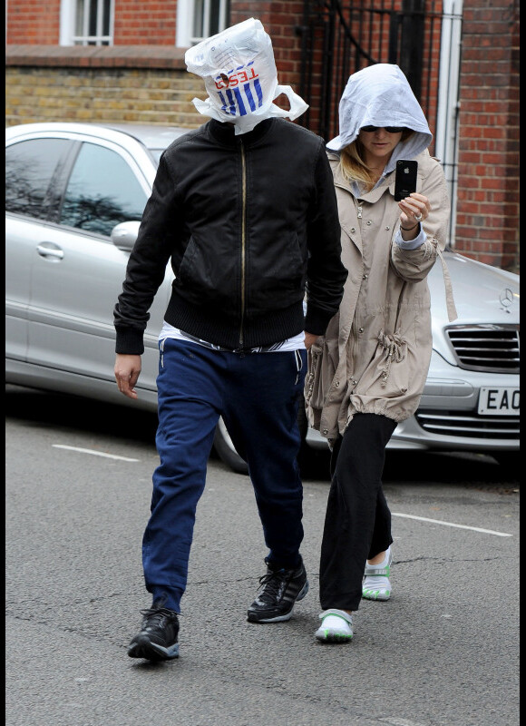 Matthew Bellamy, sac sur la tête et Kate Hudson, capuche et lunettes de soleil tentent d'échapper aux paparazzi sur la tête le 1er décembre 2011