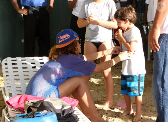 Rihanna se pose quelques minutes pour discuter avec deux enfants à la Barbade le 29 décembre 2011
