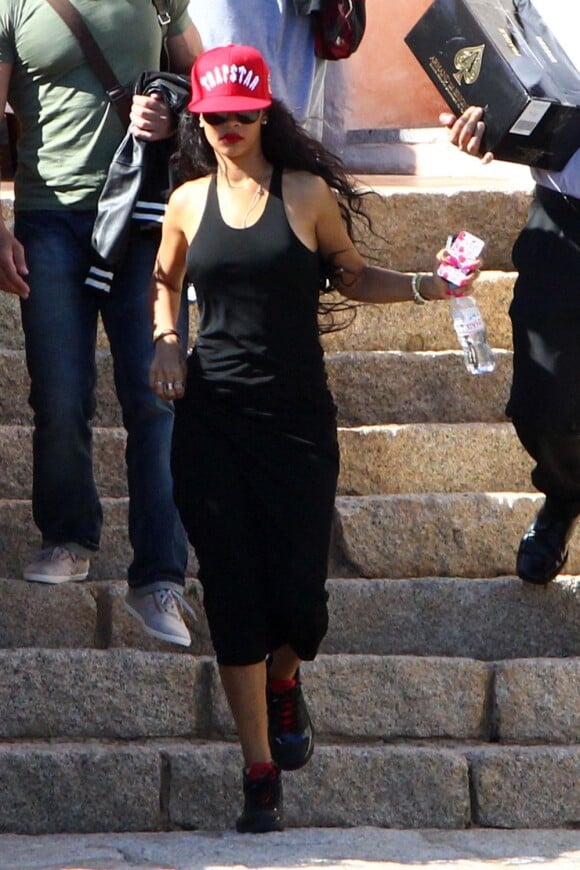 Rihanna, habillée d'une casquette Trapstar, d'une robe noire et de baskets Air Jordan, sort de son hôtel, le Cala Di Volpe. Porto Cervo, le 15 juillet 2012.