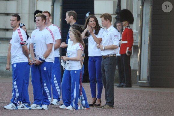 Kate Middleton, le prince William et le prince Harry, vêtus du T-Shirt officiel de la délégation olympique britannique, ont assisté au passage du relais de la flamme olympique à Buckingham Palace, le 26 juillet 2012, à l'avant-dernier jour du périple. Ils ont applaudi le relais entre Wai-Ming et John Hulse.