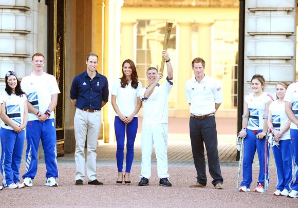 Le duc et la duchesse de Cambridge et le prince Harry, vêtus du T-Shirt officiel de la délégation olympique britannique, ont assisté au passage du relais de la flamme olympique à Buckingham Palace, le 26 juillet 2012, à l'avant-dernier jour du périple. Ils ont applaudi le relais entre Wai-Ming et John Hulse.