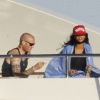 Couverte d'une couverture, Rihanna découvre en compagnie d'un ami son yacht le Latitude en Sardaigne le 15 juillet 2012