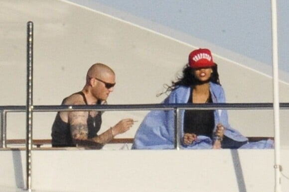 Couverte d'une couverture, Rihanna découvre en compagnie d'un ami son yacht le Latitude en Sardaigne le 15 juillet 2012