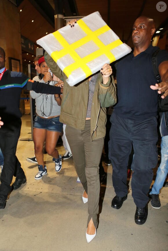 Rihanna, harcelée par les fans et les photographes à son arrivée à Gare du Nord, se cache derrière un tableau. Paris, le 1er septembre 2012.