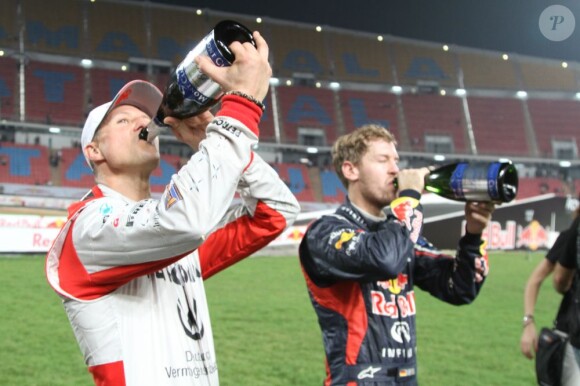 Michael Schumacher et Sebastian Vettel s'offrent une petite gorgée de champagne après leur victoire sur l'épreuve de la Nations Cup durant la Race of Champions à Bangkok le 15 décembre 2012
