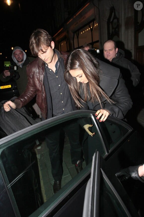 Ashton Kutcher protège sa compagne Mila Kunis à la sortie du Trendy scotts Restaurant à Londres le 14 mars 2013.