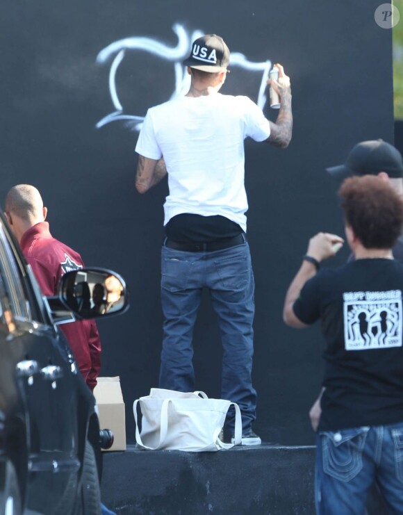 Chris Brown, bombe à la main, fait des graffitis pour une oeuvre de charité sur un mur à Miami, le 26 mars 2013.