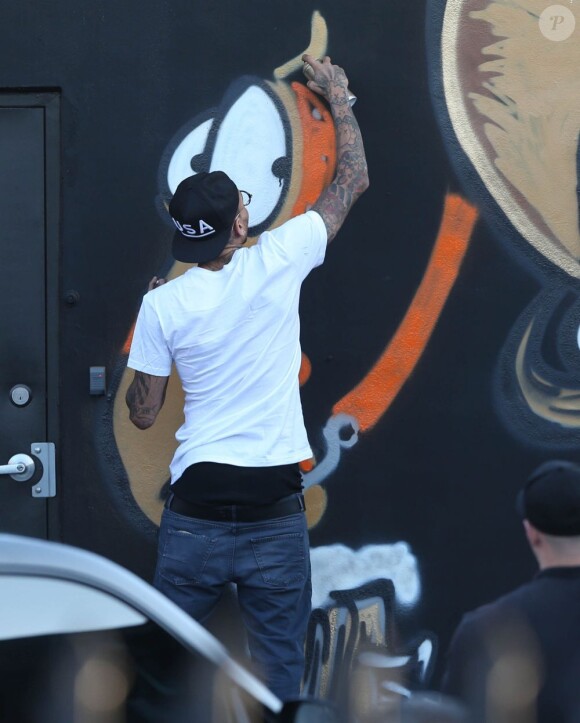 Chris Brown fait des graffitis pour une oeuvre de charité sur un mur à Miami, le 26 mars 2013.
